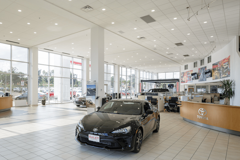 Bright, open automotive showroom with floor-to-ceiling glass, integrated lighting system, and coordinated interior layout—engineered to enhance customer experience, brand presentation, and operational efficiency.