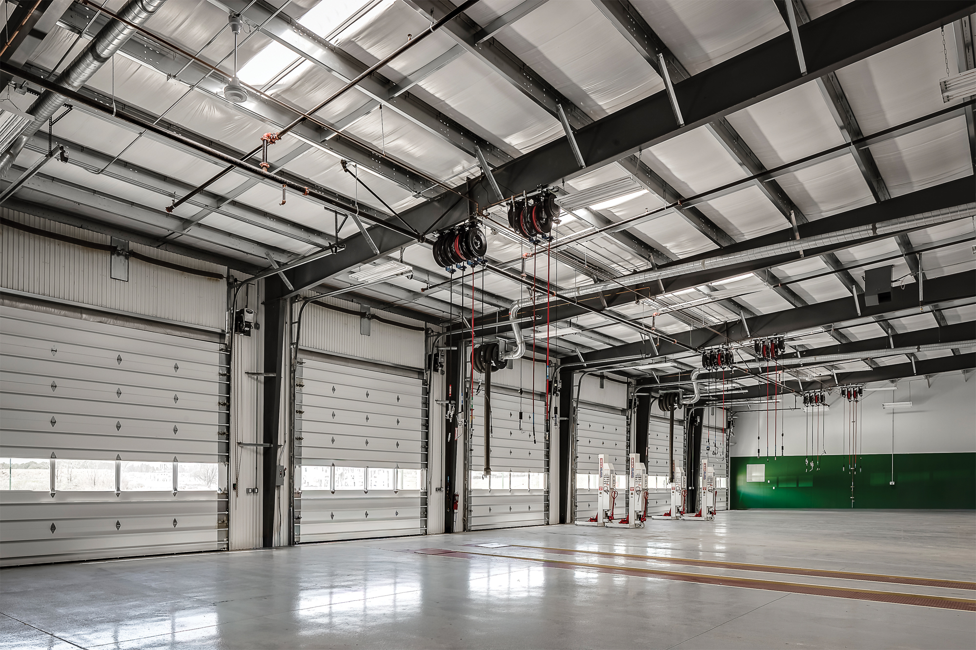 Industrial metal building interior with multiple overhead doors, exposed steel framing, and polished concrete floor
