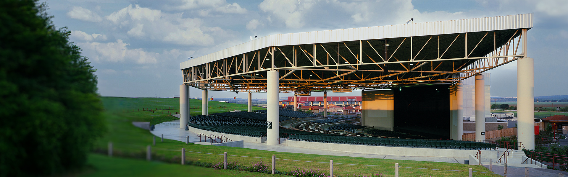 Open-air amphitheater with steel roof canopy, exposed trusses and tiered seating