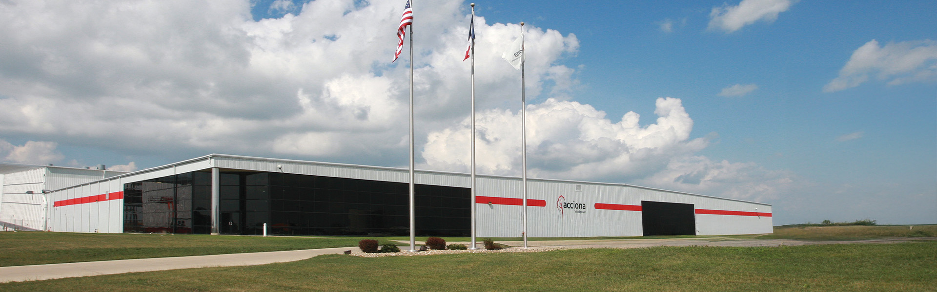 White steel production facility building with vertical rib paneling and large overhead bays