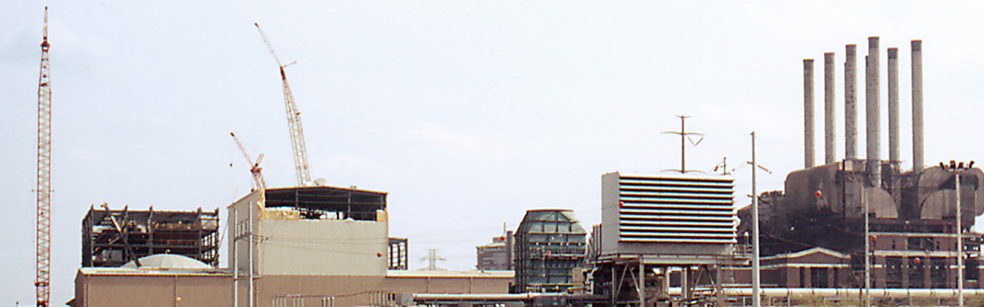Industrial generation site with cranes, steel framing and rooftop mechanical equipment