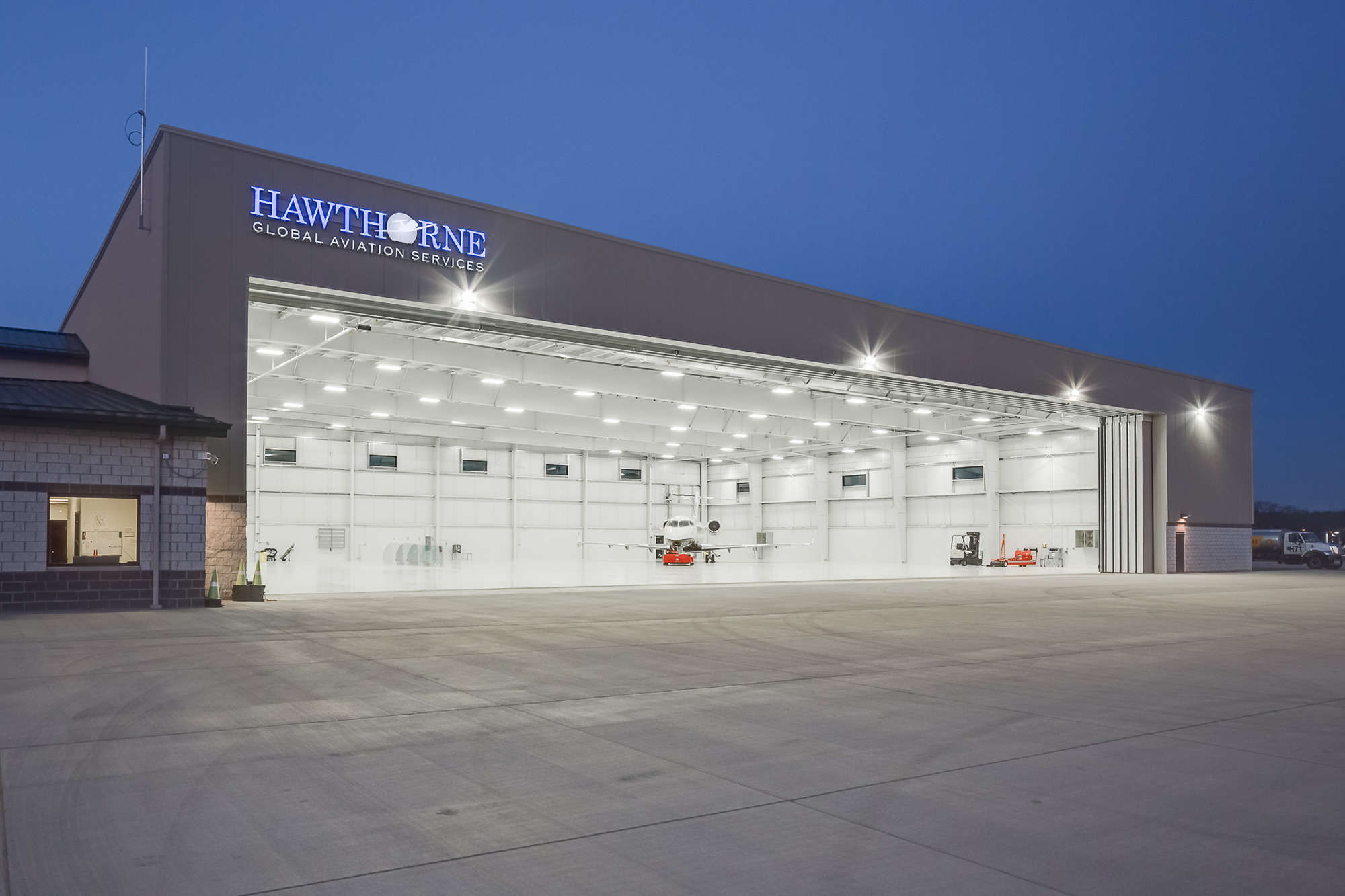 Hawthorne Global Aviation Services aircraft hangar at dusk, featuring a wide-span steel structure and expansive hangar doors designed to support efficient aviation operations.