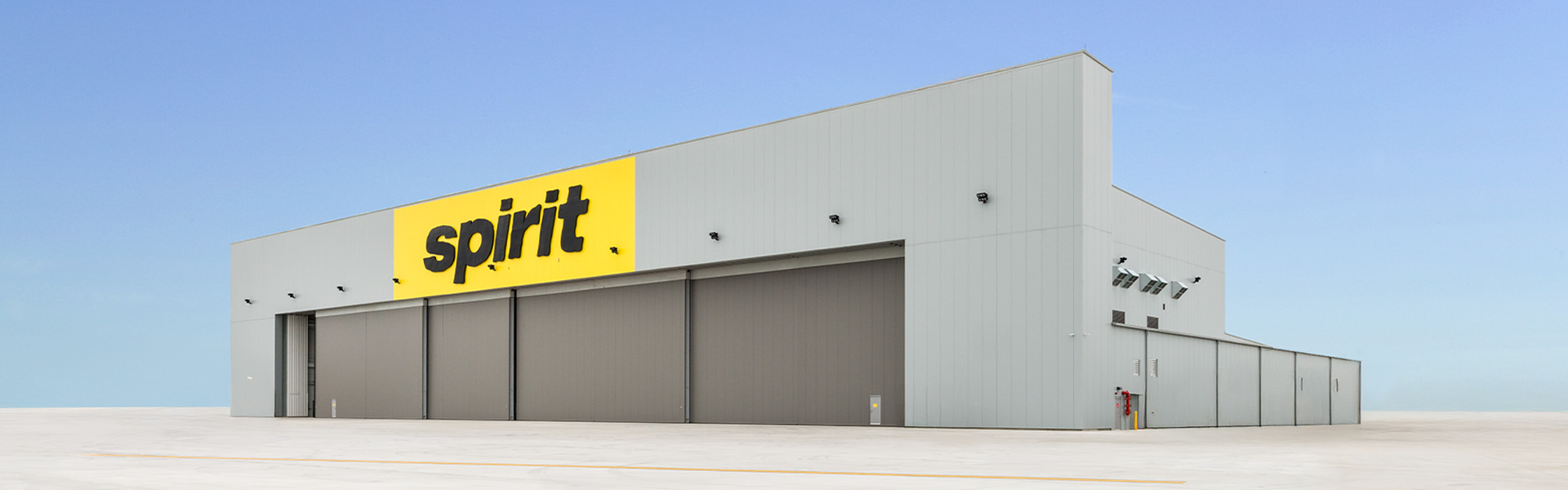 Spirit Airlines maintenance hangar with light gray metal wall panels and large hangar door opening