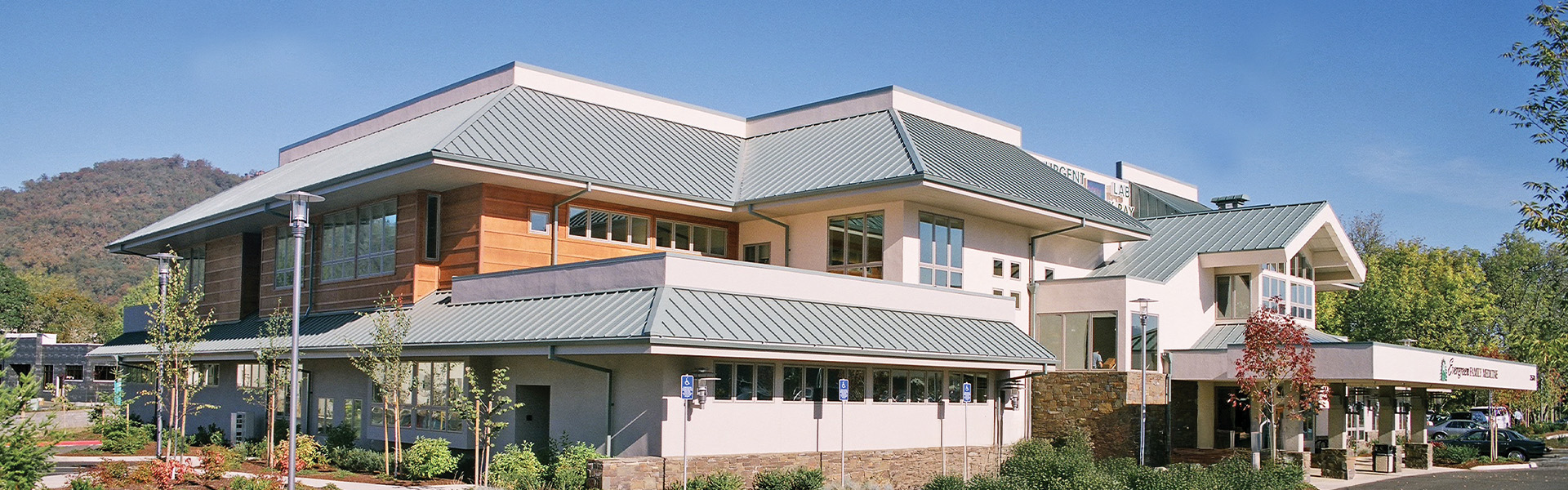 Evergreen Family Medical exterior with light-gray standing-seam metal roofs and wood siding accents