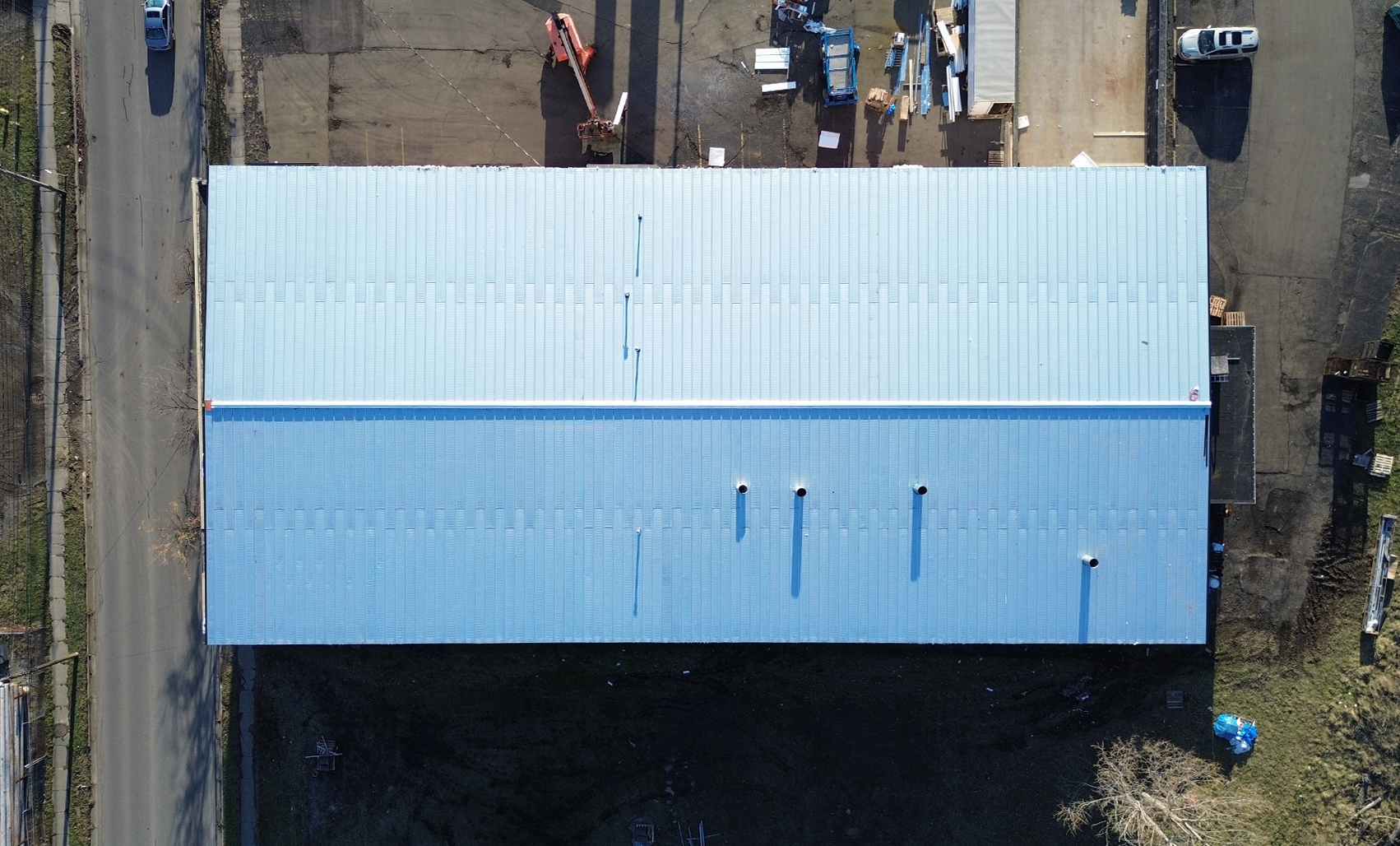 Aerial view of a commercial building’s light blue metal roof, highlighting Butler’s engineered roofing solutions for long-term durability and building protection.