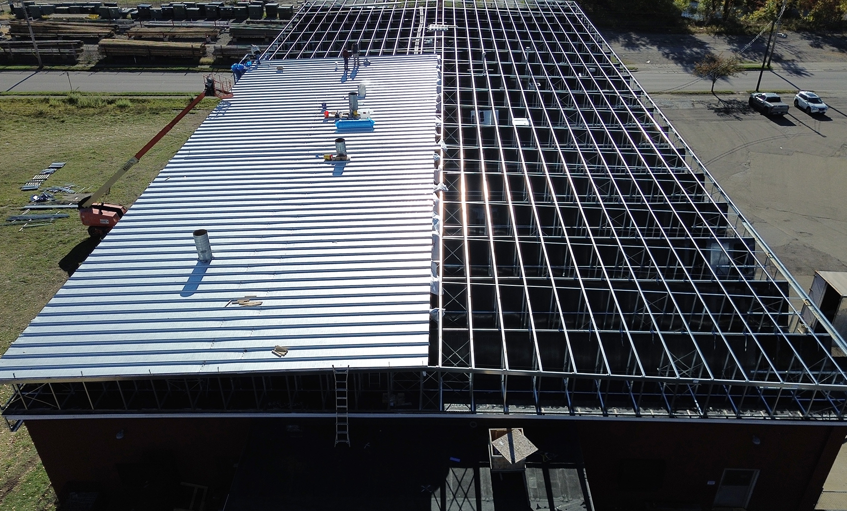 Aerial view of a Butler roof retrofit in progress, showing new metal roof panels installed alongside exposed steel framing to extend the building’s service life and improve long-term performance.