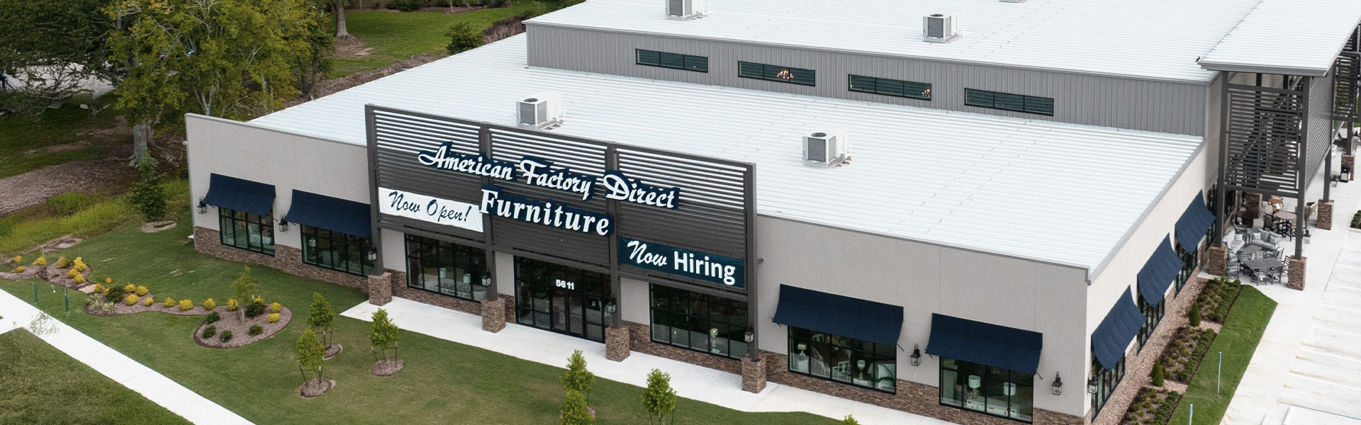 Aerial view of a retail building with white metal roof, gray steel panel facade and storefront awnings
