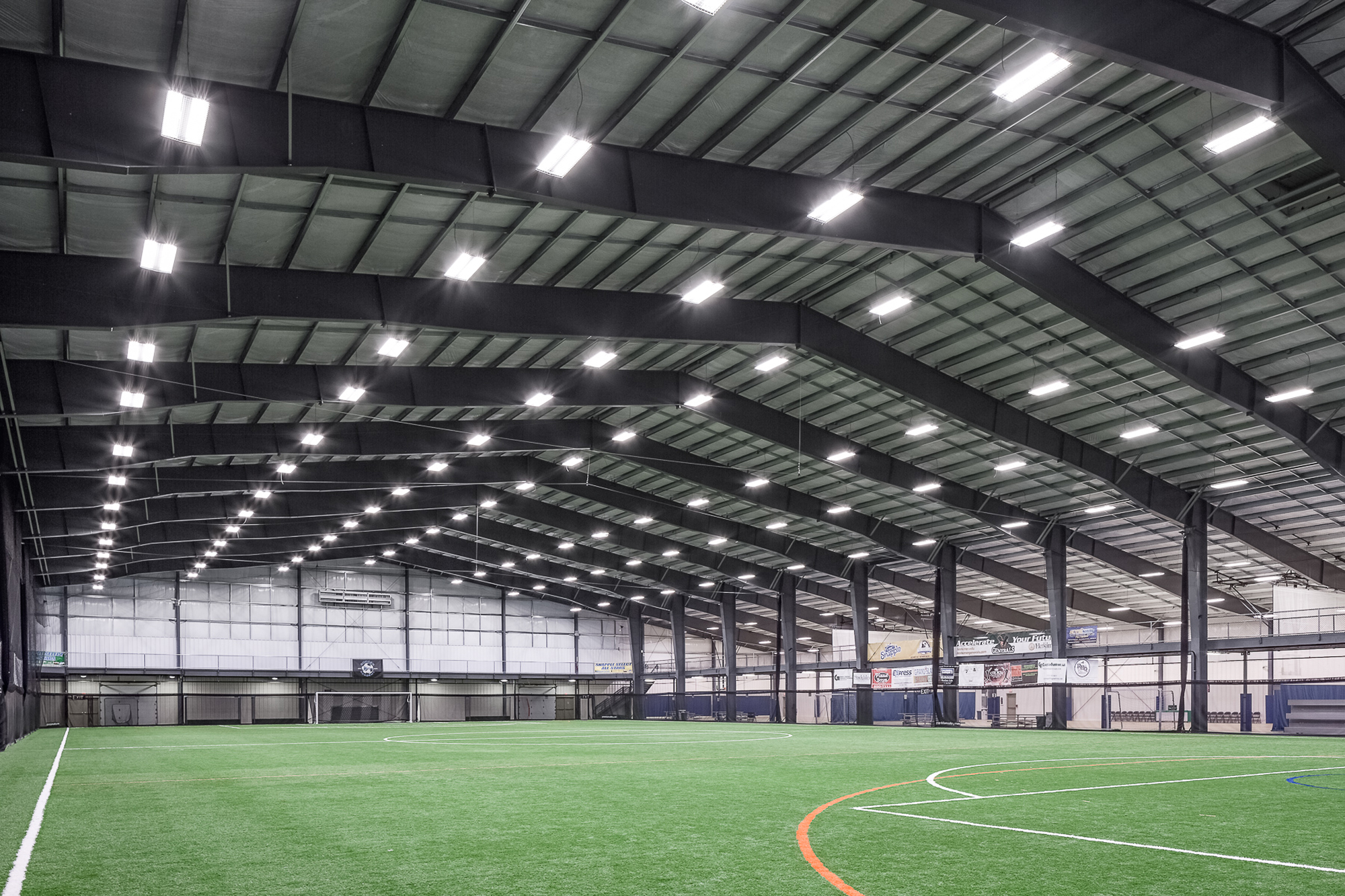 Accelerate Sports indoor turf field with exposed steel roof framing, metal roof deck and netted walls