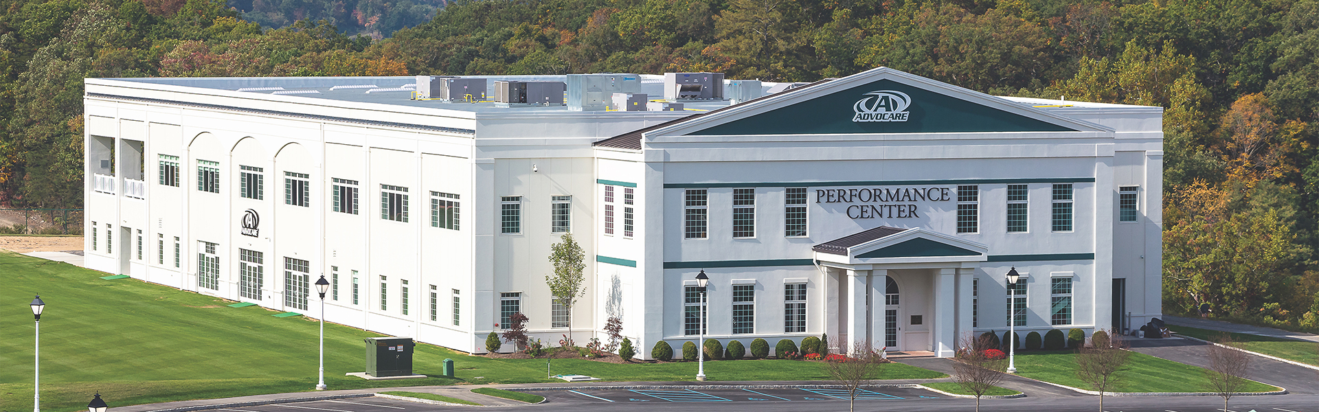 Large white training center with classical entry portico, arched windows and landscaped lawn