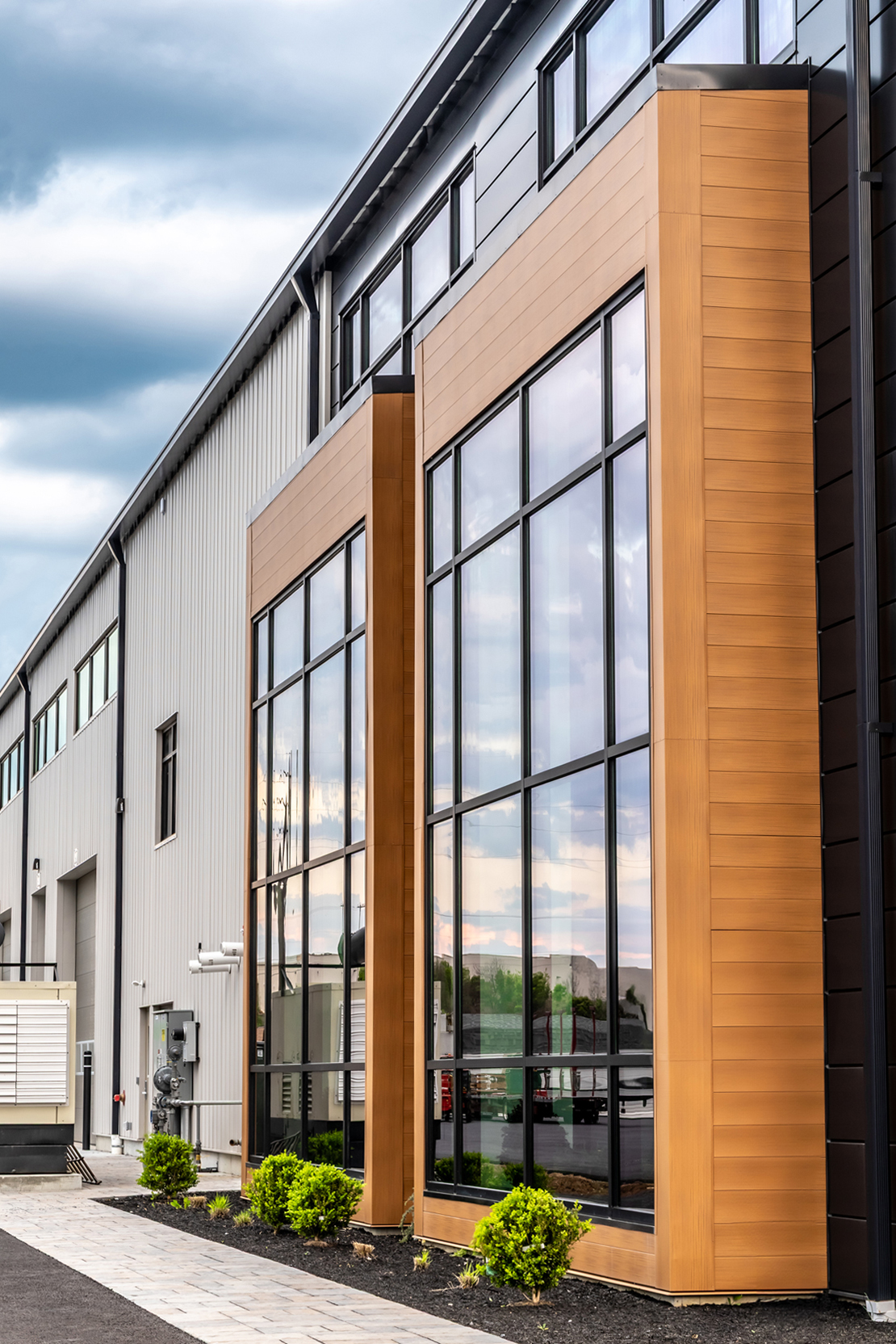 Sheds Unlimited facade with floor-to-ceiling glazing, wood-look vertical accent panels and light gray wall cladding