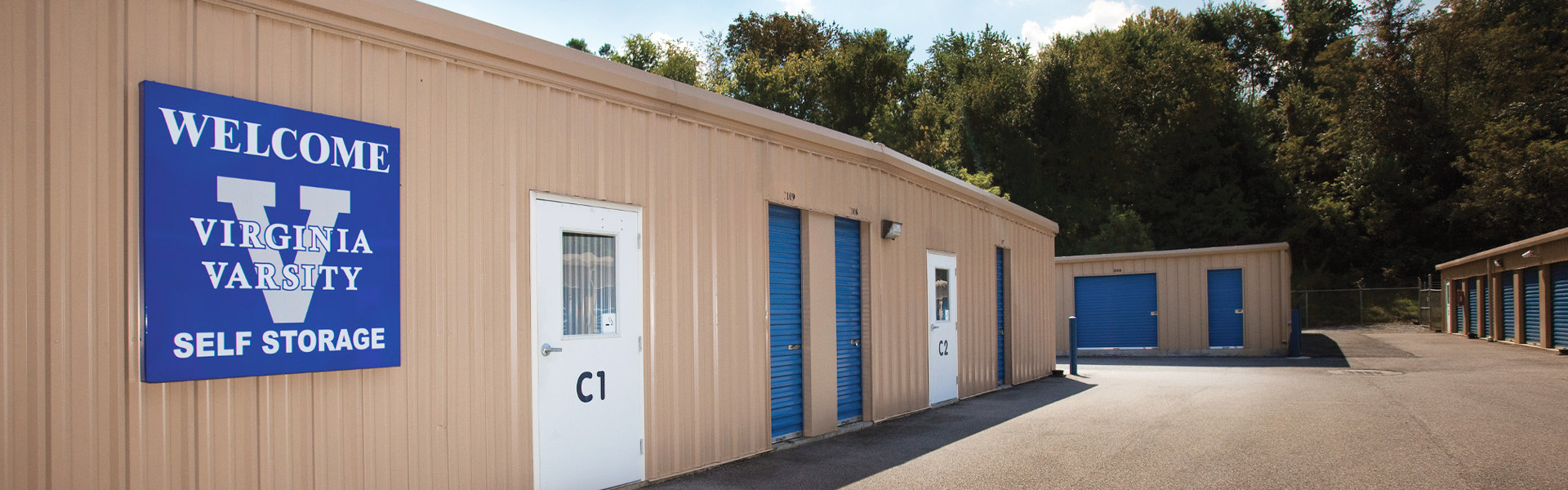 Self-storage facility buildings with tan vertical-ribbed metal wall panels and blue roll-up doors