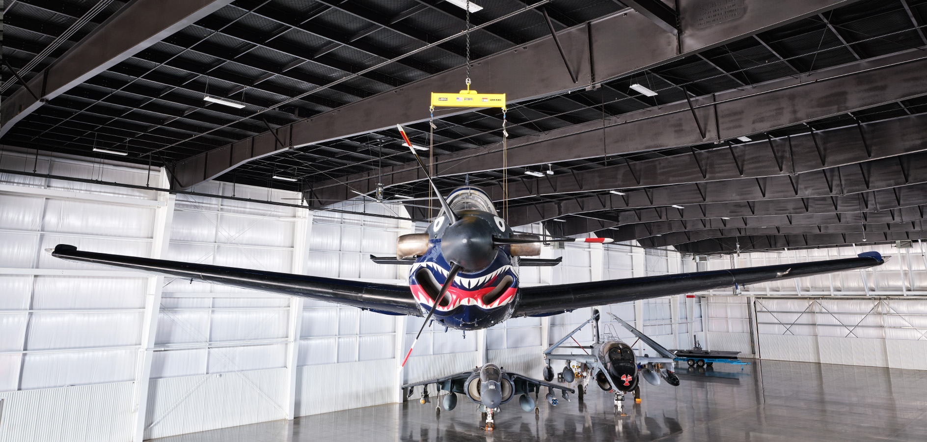 Aircraft hangar interior with black steel roof trusses and dark roof deck