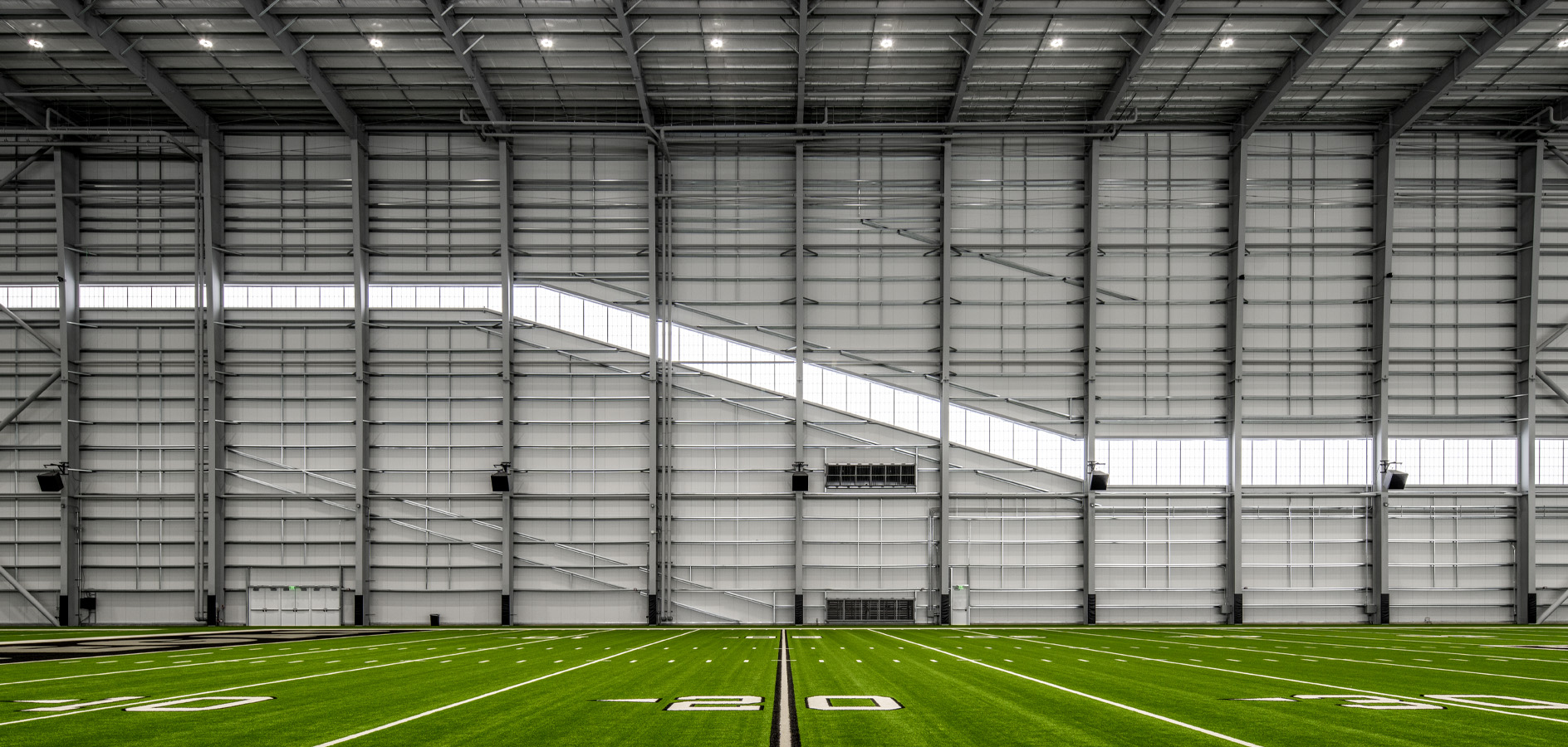 Indoor practice facility with vertical metal liner panels, diagonal clerestory glazing and exposed steel framing
