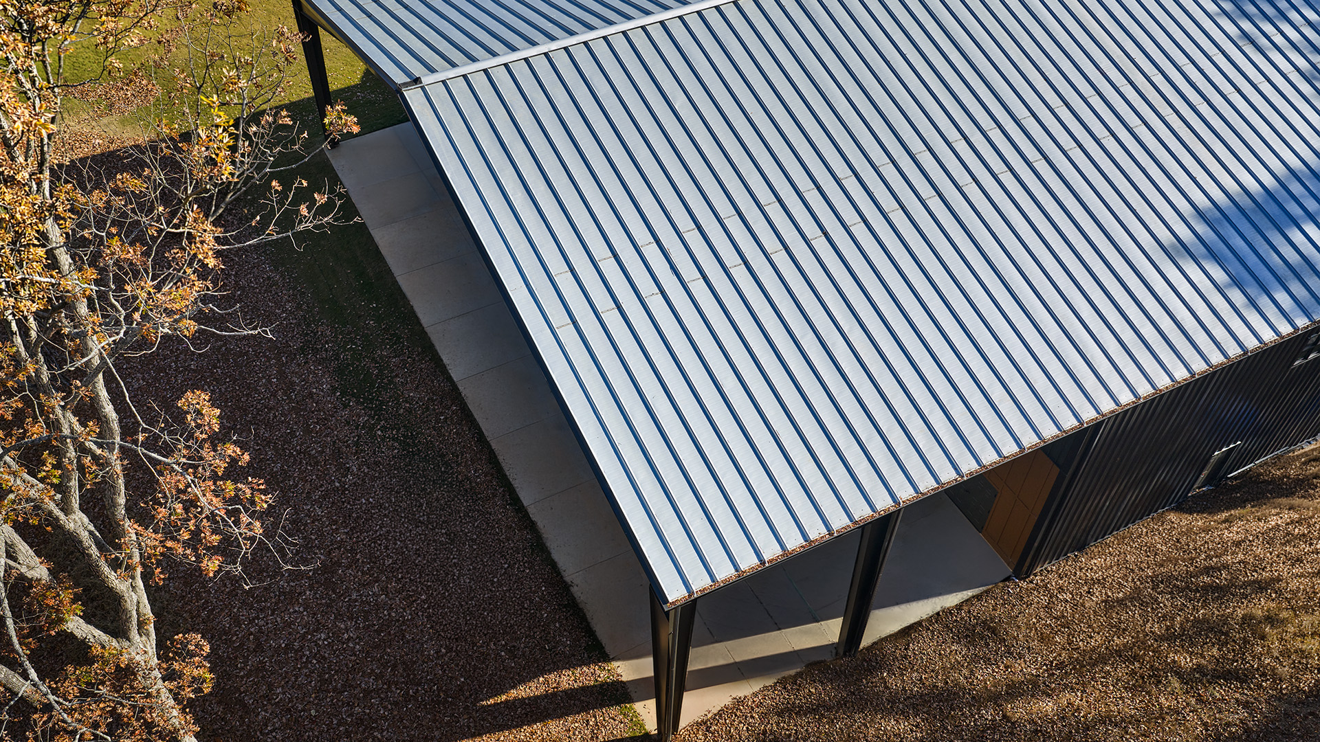 Dark vertical rib metal wall with two windows beneath a white standing-seam metal roof